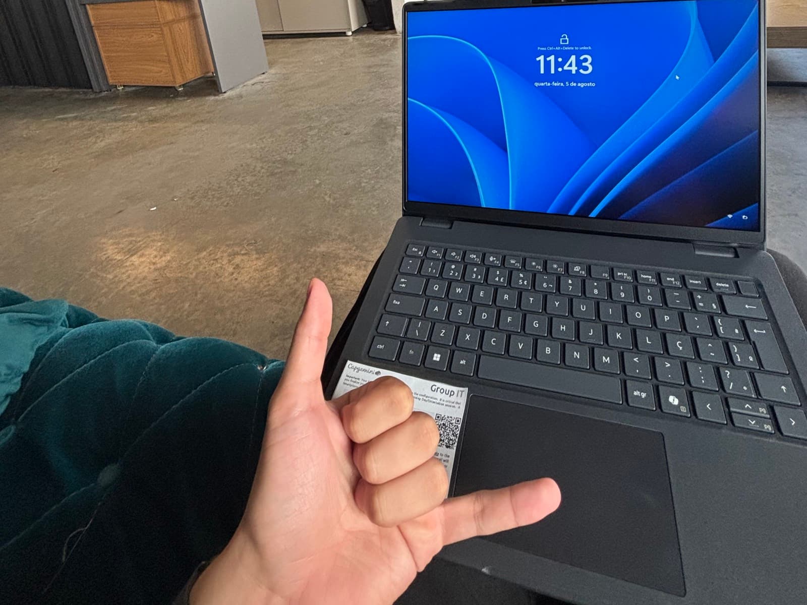 Mão fazendo o gesto de hang loose na frente do notebook de trabalho, no primeiro dia no novo escritório